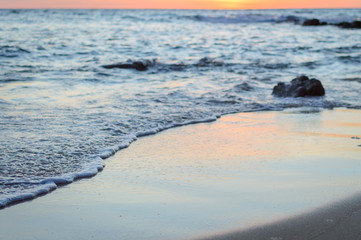 Wave of the sea on the sand beach. Seashore on sunset