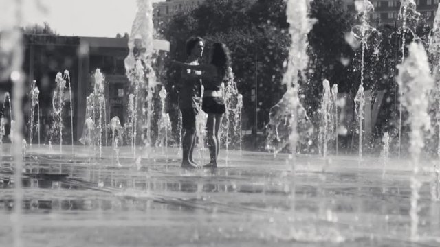 Young happy couple dancing in the fountain
