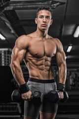 Fototapeta na wymiar strong and handsome young man doing exercise with dumbbells