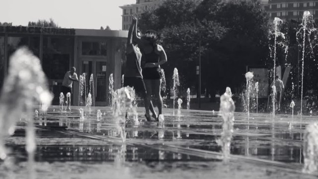 Young happy couple dancing in the fountain