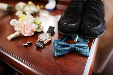 Close-up photo of groom's wedding shoes, bow tie, watch, cufflinks and buttonhole flowers.