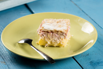 Cream pie with raspberry on the green plate in natural light above blue table