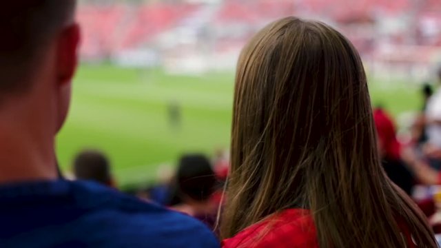 Closeup Of 2 Sports Fans Pointing To Professional Soccer Players On Field, Teen Girl Looks Excited/Surprised, She Points Again, Turns And Smiles At Camera (Slow Motion)