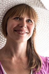 Portrait of a beautiful smiling face of caucasian woman in a summer hat against the sun on a white isolated background