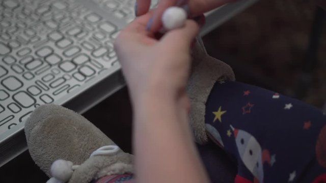 Close up shot of female hands putting on soft warm shoes on a baby feet