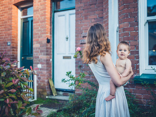 Mother with baby outside house at sunset