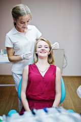 Gorgeous young female dentist checking her patient's teeth up in a specially-equipped cabinet.