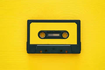 Poster Retro cassette tape over yellow wooden table. top view. © tomertu