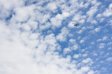 Helicopter flyes on cloudy sky. 