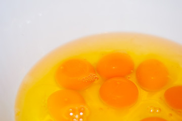 Many raw egg yolk and white in a white bowl. Coocking. Prepare the food. Ingredients. Closeup. Background.