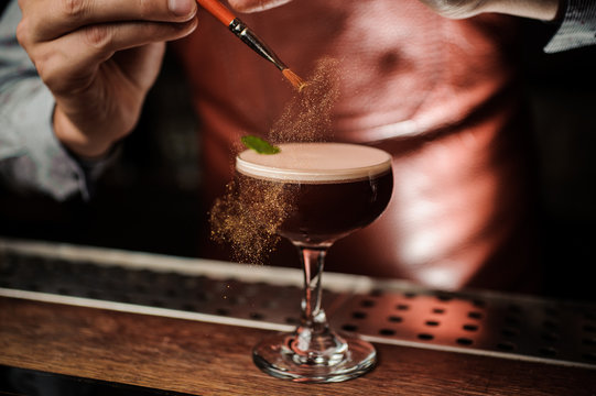The barman decorates the cocktail with a gold powder