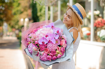 Fototapeta premium Beautiful mixed flower bouquet hold by smiling woman. Selective focus