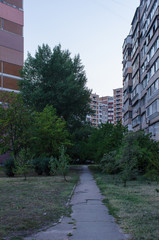 small path leading up to an old soviet era residential buildings framing the trees below them in Kiev, Ukraine, during the blue hour in summer