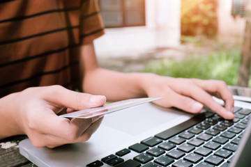 shopping online concept, woman using laptop to shopping inline and hold credit card outdoor park.