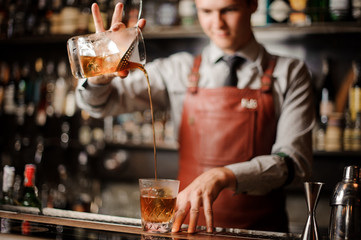 Barman in bar interior making alcohol cocktail.