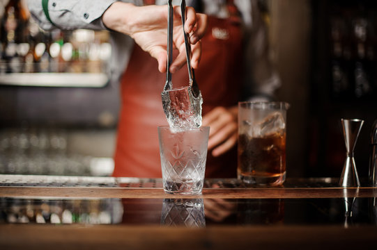 A professional bartender is holding an ice.