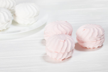 White and pink marshmallows on a white wooden table. Beautiful light background. Food
