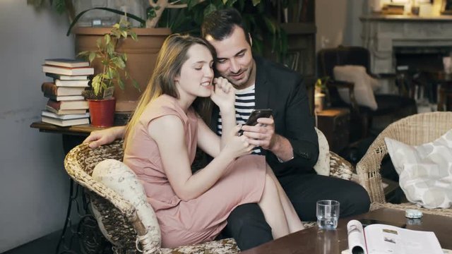 Married couple having fun using a smartphone in a cozy apartment