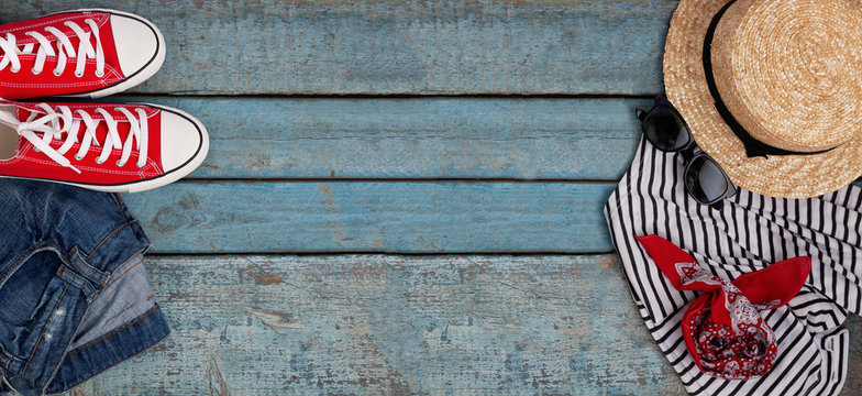 Still life of various items for recreation, clothing, hat, sneakers, camera, passport, telephone, sunglasses, tickets, headset on a wooden blue background. Concept of youth travel, light, economy