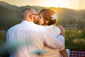 Couple kissing on picnic with sunset view