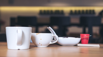 Many white coffee cups and dessert plate on wooden table in vintage cafe