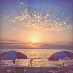 Scenic sunset over Adriatic sea beach in Durres, Albania and a silhouette of a boy running. 