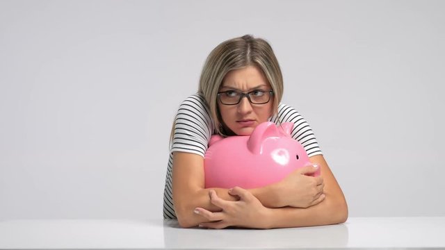 Scared woman trying to protect her piggybank from being stolen
