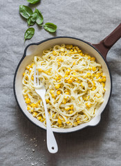 Creamy corn pasta in a cast iron skillet on a light background, top view © okkijan2010