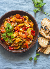 Healthy vegetarian lunch - stewed garden vegetables. Vegetable ratatouille and grilled bread. On a blue background, top view