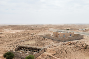 Sheepfold and a building in the middle of an arid desert with a horizon line