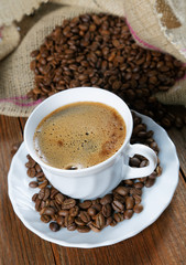 Cup with coffee on the table next to coffee beans