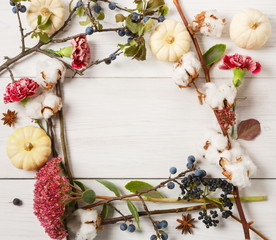 Autumn frame of dried flowers on white wood background