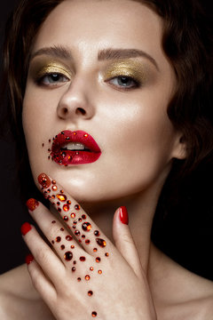 Beautiful girl with evening make-up, red lips in rhinestones and design manicure nails. beauty face. Photos shot in studio
