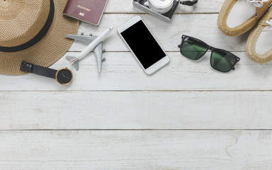 Top view women accessoires to travel concept.White mobile phone,airplane,hat,passport,watch,sunglasses on wood table.