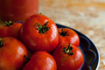 Fresh red tomatoes on blue plate on wooden table background