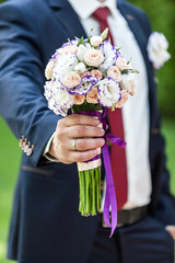 Groom holding wedding bouquet outdoors