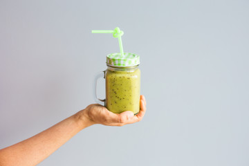 Healthy green smoothie in woman's hand. Vegan, raw food, detox and diet lifestyle.