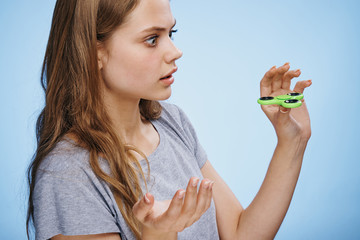 Beautiful young woman on a blue background holds a spinner
