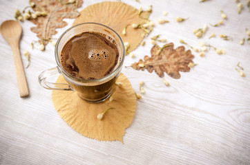 Hot coffee on rustic table with leaves. Autumn time.