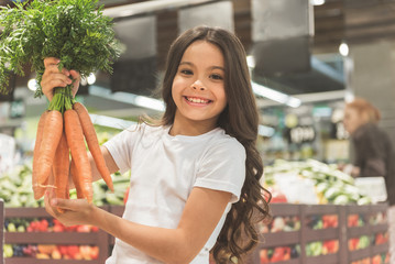 Cheerful young child holding vegetables in arms