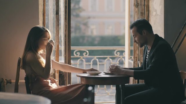 Loving man gently kissing a modest girl in a cafe. Romantic kiss a loving couple