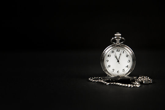 Monochrome image of an isolated pocket watch on a black background