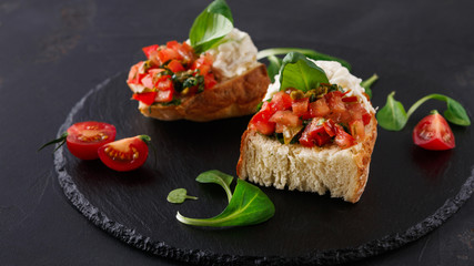 Bruschetta with cheese and vegetables on black background