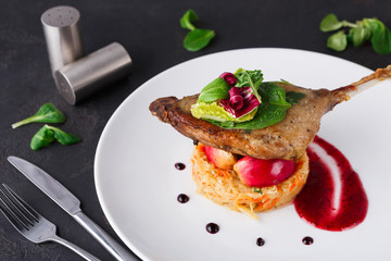 Restaurant meals. Duck confit with vegetables on black background