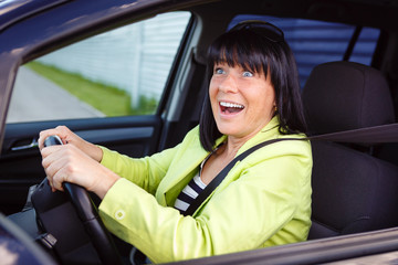 Scared and surprised woman with big eyes holds the steering wheel with both hands shouts driving the car - outdoors