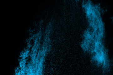 Abstract blue powder splatted on white background. Freeze motion of blue powder exploding on...