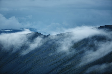 the austere Icelandic landscape with the mountains and the fjords in the background. fog under the mountain ridge
