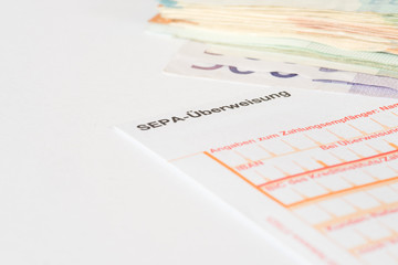 Euro Geldscheine und ein Formular für eine Bank Überweisung