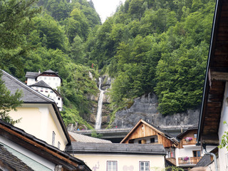 Fototapeta na wymiar Town Hallstatt with mountain waterfall. Alpine massif, beautiful canyon in Austria. Salzburg Alpine valley in summer, clear water. Destination for vacation, hiking and relaxation.