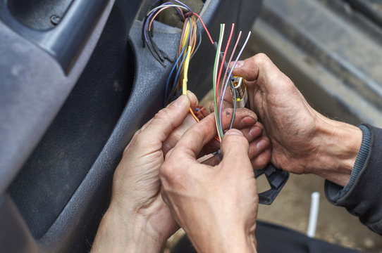 Mechanics connecting electrical wires in the door of car using a lighter  